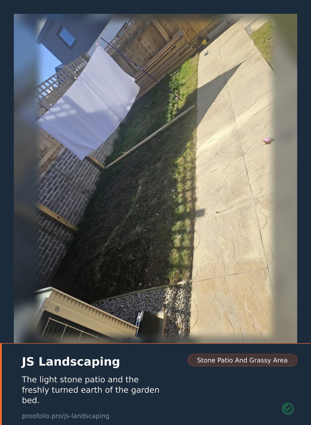 A white sheet hangs on a washing line in a garden with paved and grassy areas.