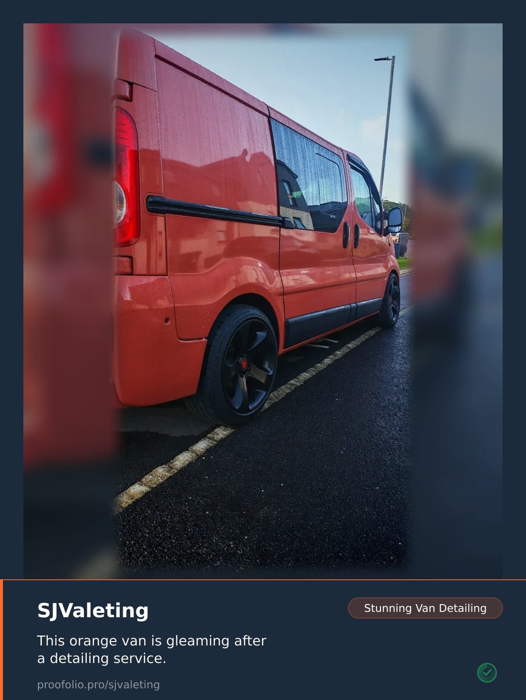 A bright orange van with black wheels is parked on an asphalt surface that has visible water droplets.