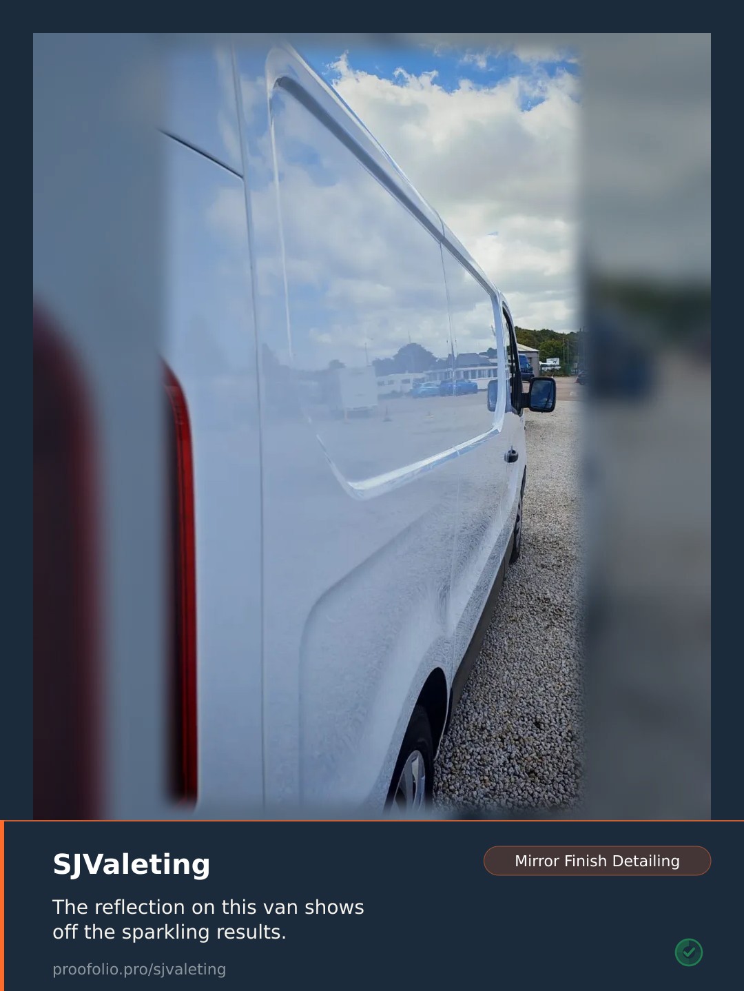 A white van sits on a gravel lot, its side reflecting the clouds and sky.